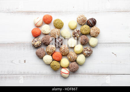 Schokoladentrüffel Bonbons in Herzform auf weißem Holz Hintergrund angeordnet Stockfoto