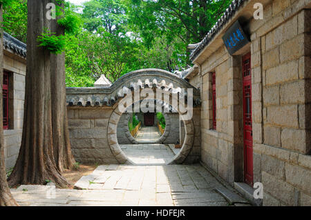 Geschwungenen Torbögen, Zypressen und chinesische Architektur innerhalb des taoistischen Taiping-Tempels in Qingdao China in der Provinz Shandong. Stockfoto