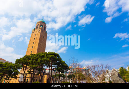 Uhr Turm erhebt sich über den Bäumen auf dem Campus des Daejeon Institut für Wissenschaft und Technologie an einem Tag blauer Himmel in Korea Stockfoto