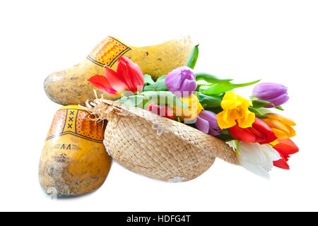 Holländische Holzschuhe mit Strohhut und bunte Tulpen über weiß Stockfoto