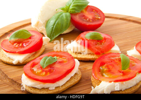 Italienische Tapas mit Käse Tomate und Basilikum auf einer Holzplatte Stockfoto