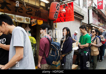 Japanische Leute und Reisende Ausländer stehen Schlange kaufen Takoyaki ist eine kugelförmige japanische Snack Shop in Ameyoko Markt in Ueno am 21. Oktober 2 Stockfoto