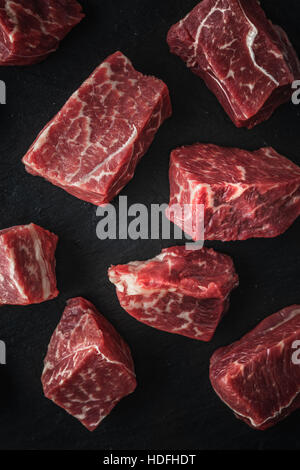 Rohe Angus-Rindfleisch-Scheiben auf den schwarzen Stein Tabelle vertikal Stockfoto