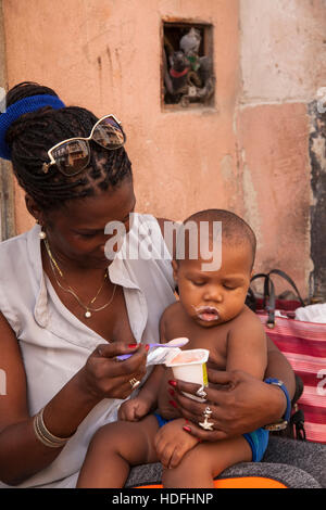 Eine Frau, füttern ihr Baby Joghurt in Zentral-Havanna, Kuba. Stockfoto