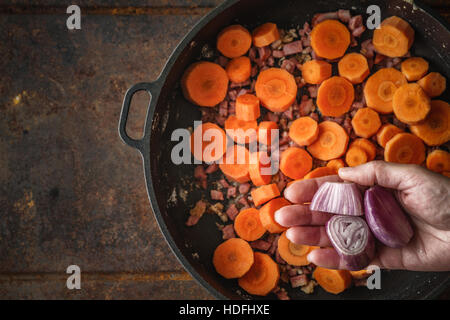 Schalotte in der Pfanne mit Speck und Karotten Draufsicht hinzufügen Stockfoto