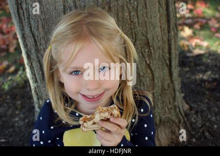 entzückende schulpflichtige Mädchen essen, Erdnussbutter und Marmelade-sandwich Stockfoto