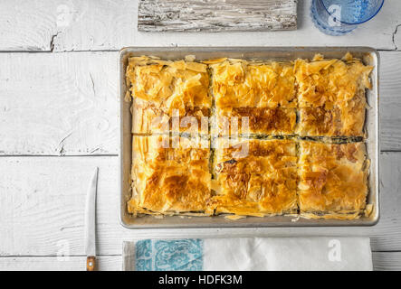 Griechischer Kuchen Spanakopita in der Metall-Pfanne mit Tabelle Ware Draufsicht Stockfoto