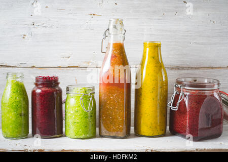 Flaschen und Glas mit verschiedenen Smoothie auf dem Holzbrett horizontal Stockfoto