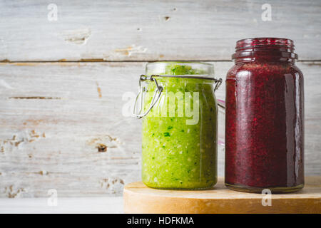 Grüne und rote Smoothie in das Glasgefäß auf dem weißen Hintergrund Holz Stockfoto