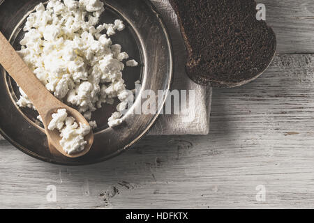 Frische Quark auf der Metallplatte mit Brot auf dem weißen Holztisch Stockfoto