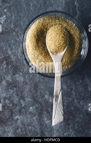 Brauner Zucker in der Glasschüssel auf dem Stein Hintergrund vertikale Stockfoto