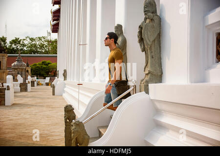 Seitenansicht der junge Mann Treppen hinunter der buddhistischen Tempel in Bangkok, Thailand und auf der Suche gerade. Stockfoto