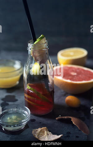 Halbleere Flasche mit Zitronensaft auf dem dunklen Stein Hintergrund Stockfoto