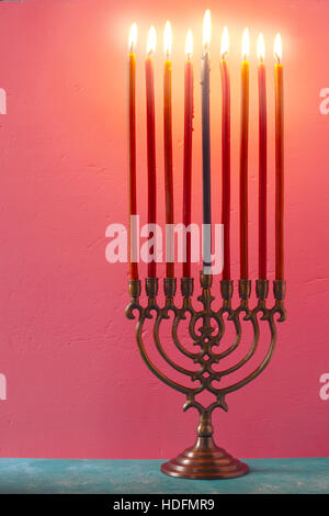 Hanukkah Menorah mit brennenden Kerzen auf dem rosa Hintergrund vertikale Stockfoto