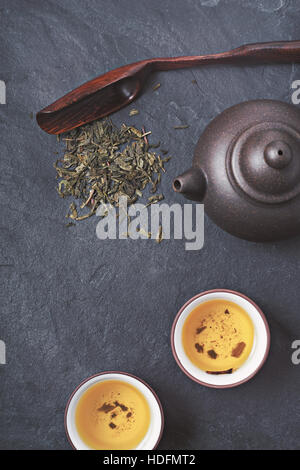 Chinesischen Teekanne und Schüssel mit grünem Tee auf dem Stein Hintergrund vertikale Stockfoto