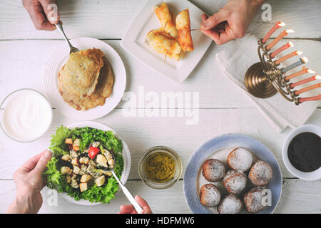 Chanukka-Abendessen mit traditionellen Gerichten auf dem weißen Holztisch Stockfoto