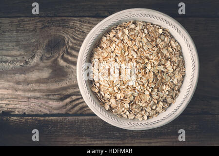 Rohe Haferflocken in die Schüssel auf der hölzernen Tischplatte-Ansicht Stockfoto