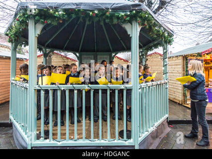 Chor der Broad Chalke School singt Weihnachtslieder in einem Bandstand, Market Square, Salisbury, Wiltshire, Großbritannien, Weihnachten 2016. Stockfoto