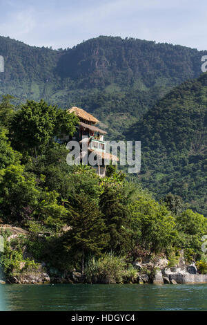 Großzügige Villa am Ufer des Lake Atitlan, Guatemala mit steilen, bewaldeten Hügel hinter und See im Vordergrund. Stockfoto