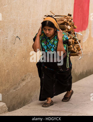 Eine Maya-Frau in traditioneller Kleidung trägt Brennholz bergauf auf dem Rücken mit einer Tumpline in Santa Cruz la Laguna, Guatemala. Stockfoto