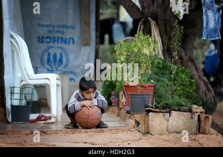 Ein syrischer Flüchtlingskind spielt mit einem Ball in eine Siedlung Camp, wo er unter einem Olivenhain im Koura, in der Nähe von Tripoli, Libanon lebt. Stockfoto