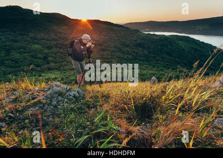 Mann auf der Wiese beim Sonnenuntergang fotografieren Stockfoto