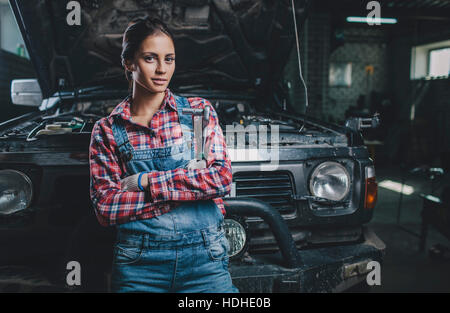 Porträt von zuversichtlich weibliche Mechaniker mit verschränkten Armen stützte sich auf Auto Werkstatt Stockfoto
