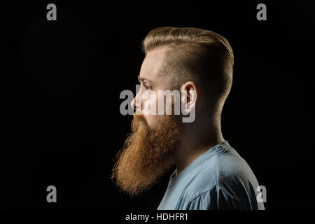 Seitenansicht des nachdenklichen bärtiger Mann vor schwarzem Hintergrund Stockfoto