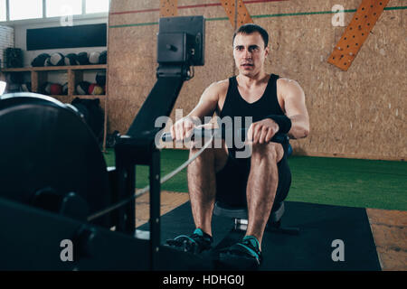 Entschlossenen Mann auf Rudergeräte im Fitness-Studio trainieren Stockfoto