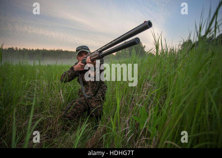 Jäger mit dem Ziel Gewehr kniend auf Feld gegen Himmel Stockfoto