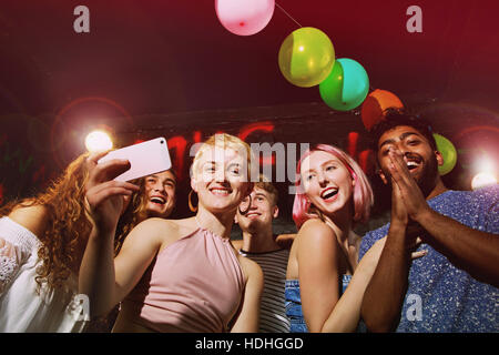 Niedrigen Winkel Porträt glücklich Frau nehmen Selfie mit Freunden am Hof Stockfoto