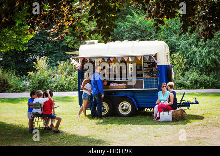 Menschen auf einen blauen mobilen Coffee Shop auf einer Wiese. Stockfoto
