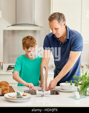 Eine Familie zu Hause. Ein Mann und ein Junge in der Küche den Abwasch nebeneinander. Stockfoto