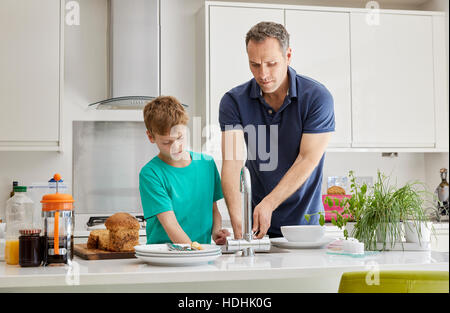 Eine Familie zu Hause. Ein Mann und eine junge tun die Lichtung und abwaschen. Stockfoto