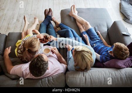 Eine Familie zu Hause.  Blick von oben auf zwei Erwachsene und zwei Kinder sitzen auf einem Sofa zusammen. Stockfoto