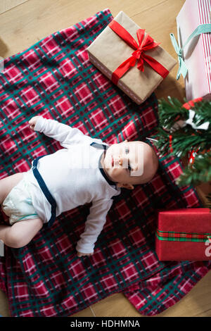 Kleinen Jungen liegen unter Weihnachtsbaum unter präsentiert Stockfoto