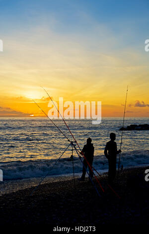 Mann und junge Angeln am Strand bei Sonnenuntergang, West Bay, Bridport, Dorset, England UK Stockfoto