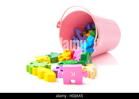 Bunte Puzzleteile mit rosa Eimer isoliert auf weiß Stockfoto