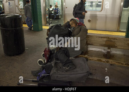 Obdachlose, psychisch kranke Frau schläft auf einer Bank auf dem Bahnsteig in einer u-Bahn-Station in Manhattan. Stockfoto