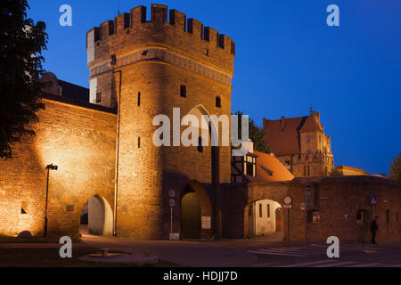 Tor (Brama Mostowa) von 1432 und Stadtmauer nachts in Torun, Polen, alte Stadtbefestigung zu überbrücken Stockfoto
