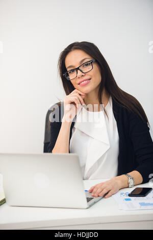 Junge Geschäftsfrau sitzen im Büro arbeiten. Lächelnd und Blick in die Kamera Stockfoto