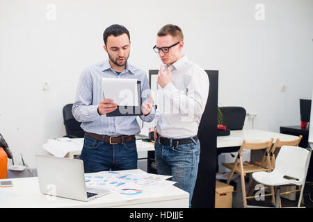 zwei kaukasischen Führungskräften in Freizeitkleidung mit einem Business-Diskussion in Büro. Stockfoto