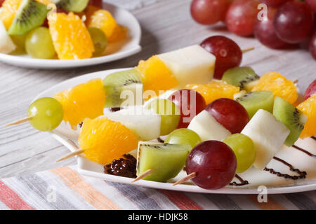 Frisches Obst am Spieß auf einem weißen Teller Nahaufnahme. horizontale Stockfoto