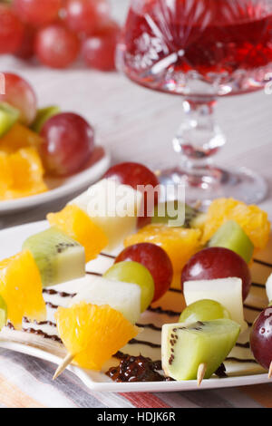 Frisches Obst auf Spieße und roten Wein close-up auf dem Tisch. vertikale Stockfoto