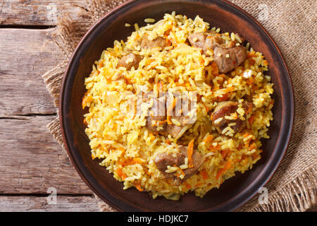 Asiatische Pilaw auf eine braune Platte Nahaufnahme. horizontale Ansicht von oben, rustikalen Stil Stockfoto