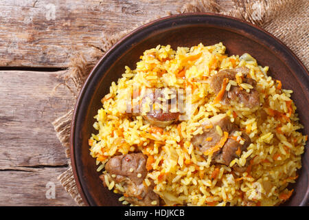 Reis mit Fleisch und Gemüse auf eine braune Platte Nahaufnahme. horizontale Ansicht von oben, rustikalen Stil Stockfoto