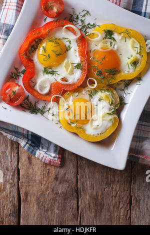 Spiegeleier mit Paprika und Tomaten auf einer Platte Nahaufnahme. vertikale Ansicht von oben Stockfoto