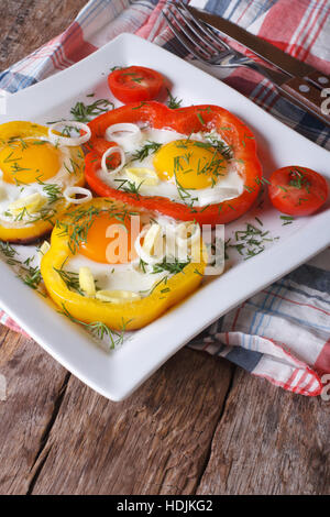 Spiegeleier mit Paprika und Tomaten auf einer Platte Nahaufnahme. vertikale Stockfoto