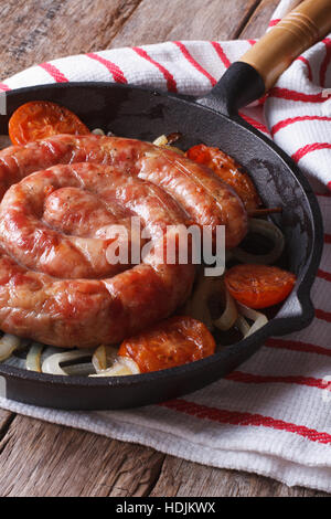 Bratwürste mit Zwiebeln und Tomaten in eine Pfanne Nahaufnahme. vertikale Stockfoto