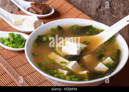 Japanische Miso-Suppe in eine weiße Schüssel mit einem Löffel auf eine Tabelle Nahaufnahme. vertikale Stockfoto